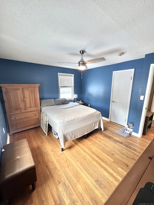 bedroom with ceiling fan, wood-type flooring, and a textured ceiling