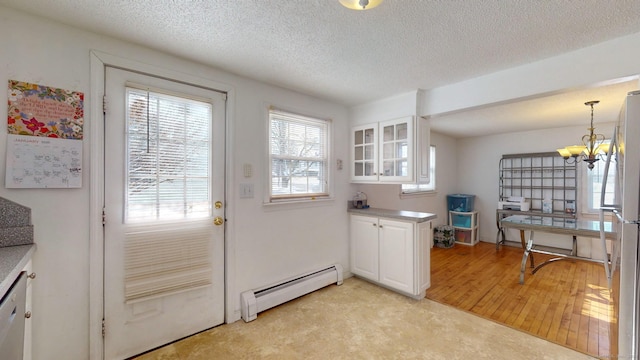 kitchen with stainless steel appliances, white cabinetry, hanging light fixtures, and a baseboard radiator