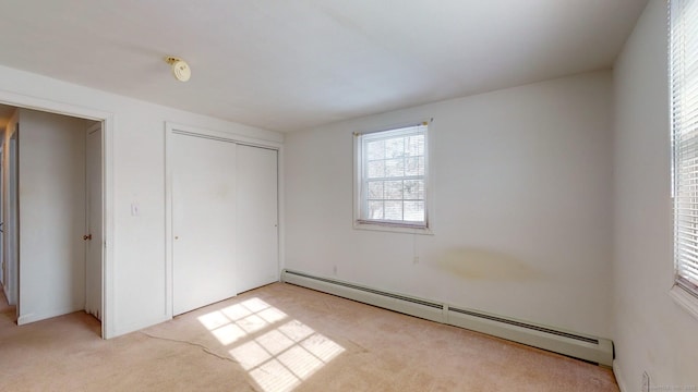 unfurnished bedroom with a baseboard radiator, light colored carpet, and a closet