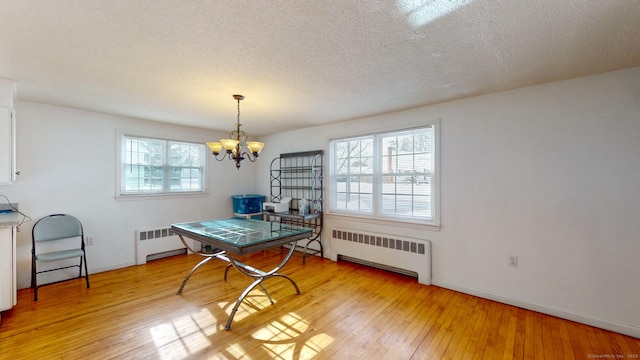 dining area with a notable chandelier, radiator heating unit, and light hardwood / wood-style floors