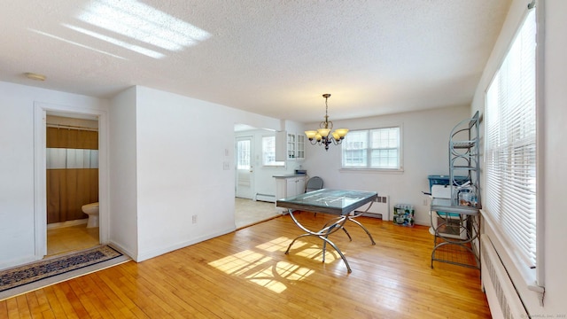 interior space featuring baseboard heating, radiator heating unit, light hardwood / wood-style flooring, a textured ceiling, and a notable chandelier