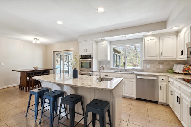 kitchen with a kitchen bar, a sink, backsplash, and appliances with stainless steel finishes