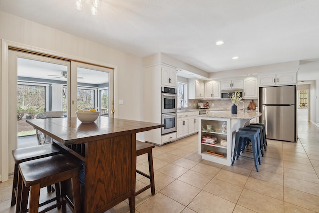 kitchen featuring a kitchen breakfast bar, open shelves, a kitchen island, appliances with stainless steel finishes, and white cabinetry