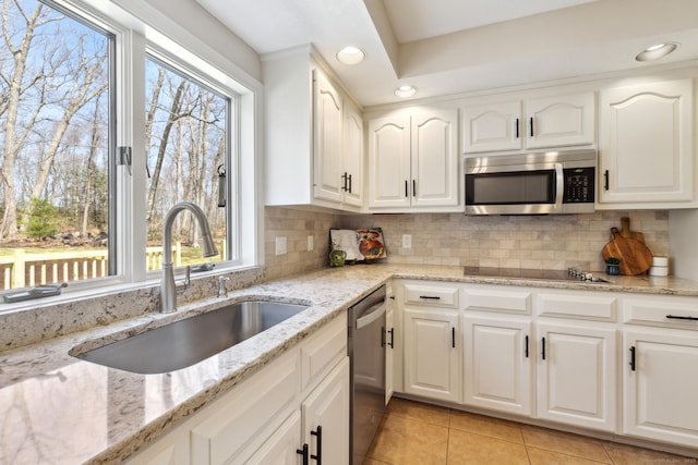 kitchen featuring white cabinets, stainless steel appliances, a sink, and light tile patterned floors