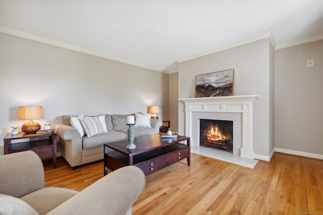 living room with a fireplace with flush hearth, baseboards, ornamental molding, and wood finished floors