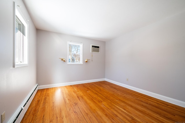 spare room featuring hardwood / wood-style flooring, a wall mounted AC, and a baseboard heating unit