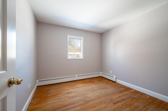 unfurnished room featuring a baseboard radiator and light hardwood / wood-style flooring