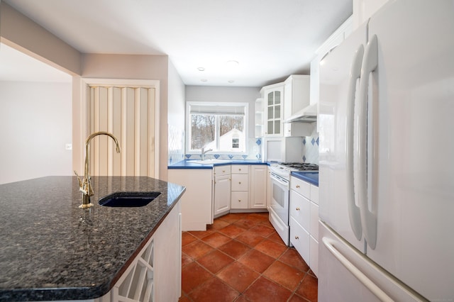 kitchen featuring sink, white appliances, white cabinets, and dark stone countertops