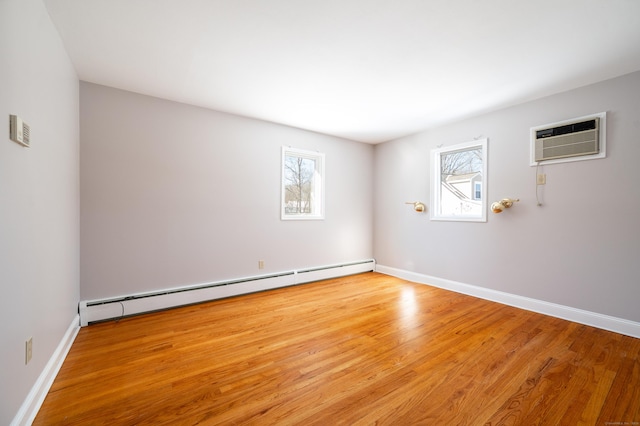 spare room featuring a baseboard radiator, light wood-type flooring, plenty of natural light, and a wall mounted air conditioner