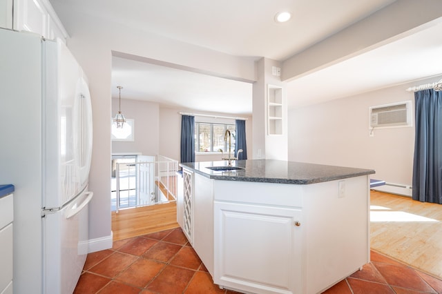 kitchen featuring baseboard heating, white cabinetry, white fridge, sink, and a wall mounted air conditioner