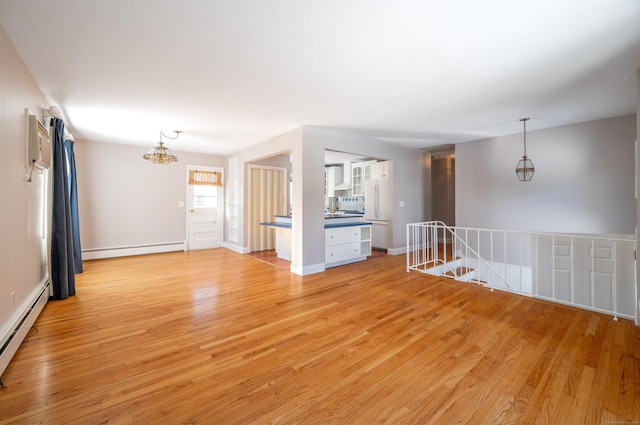 spare room with light wood-type flooring, a notable chandelier, and a baseboard radiator