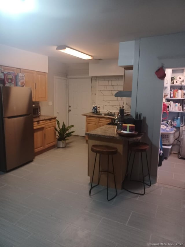 kitchen with a kitchen bar, light brown cabinets, kitchen peninsula, and appliances with stainless steel finishes