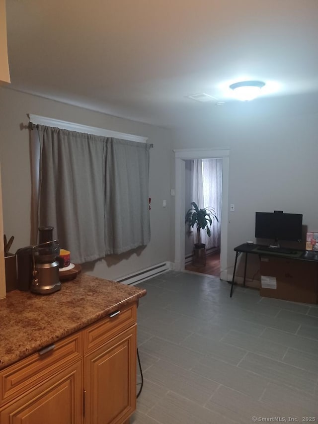 interior space with stone counters and a baseboard heating unit