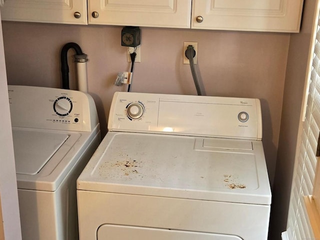 clothes washing area featuring washing machine and clothes dryer and cabinets