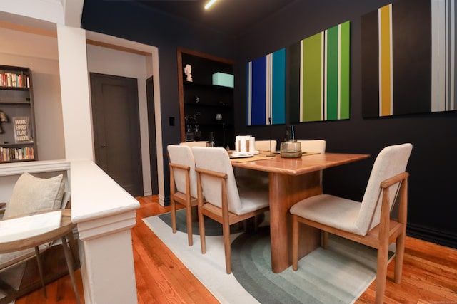 dining space with built in shelves and light wood-type flooring