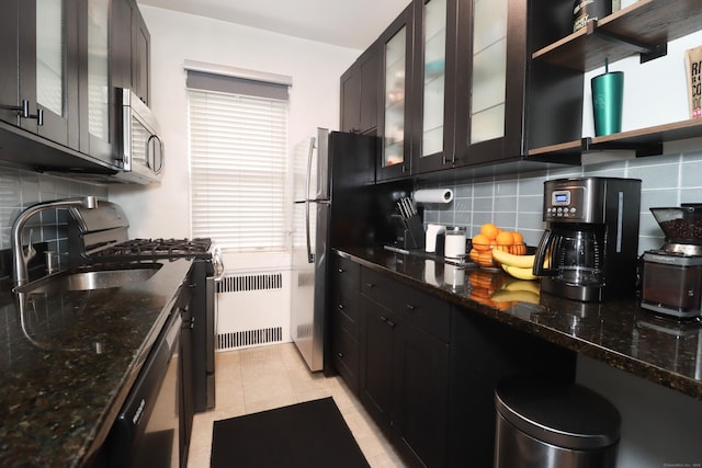 kitchen with radiator, tasteful backsplash, sink, dishwashing machine, and dark stone counters