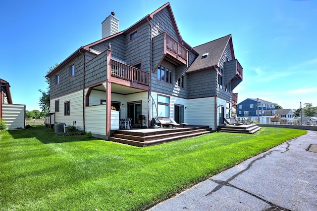 rear view of house with central air condition unit and a yard