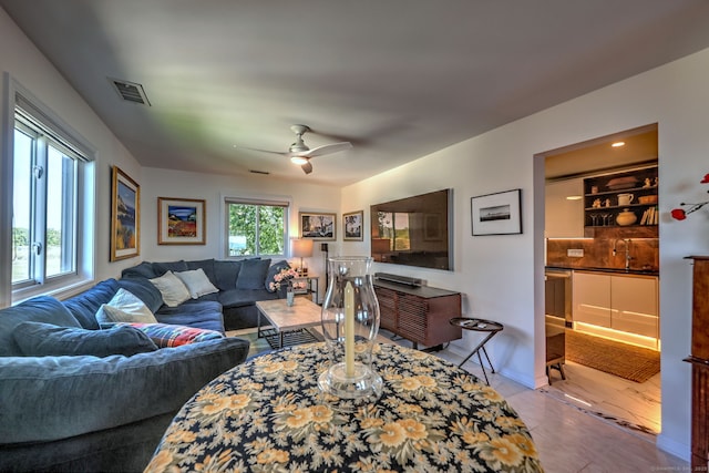 tiled living room featuring ceiling fan and sink