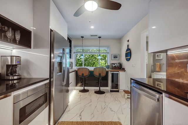 kitchen with decorative light fixtures, white cabinetry, ceiling fan, and appliances with stainless steel finishes