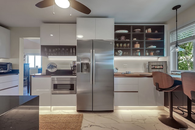 kitchen with decorative light fixtures, stainless steel refrigerator with ice dispenser, white cabinets, and oven