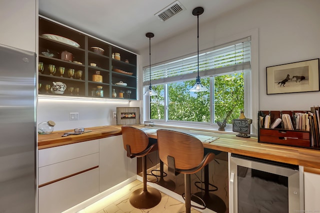 bar with decorative light fixtures, stainless steel fridge, and butcher block countertops