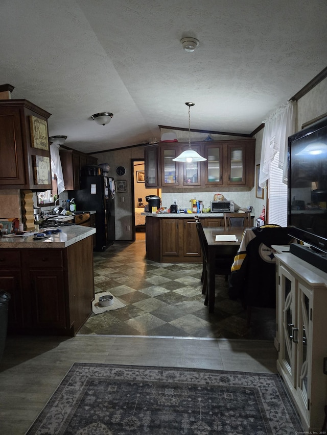 kitchen with lofted ceiling, dark brown cabinets, black fridge, and decorative light fixtures