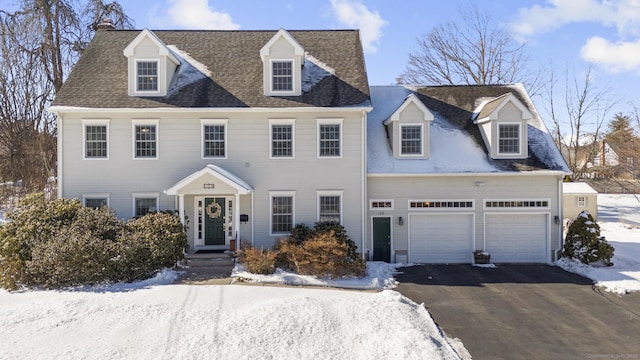 colonial home featuring aphalt driveway, an attached garage, and a shingled roof