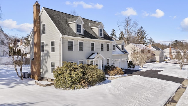 view of front facade featuring roof with shingles, a chimney, central AC unit, a garage, and a residential view