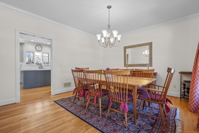 dining area with a notable chandelier, visible vents, light wood-style flooring, ornamental molding, and baseboards