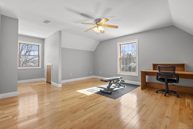 exercise area featuring a wealth of natural light, light wood-type flooring, visible vents, and vaulted ceiling