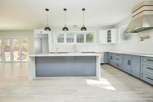 kitchen featuring pendant lighting, appliances with stainless steel finishes, white cabinetry, tasteful backsplash, and wall chimney exhaust hood