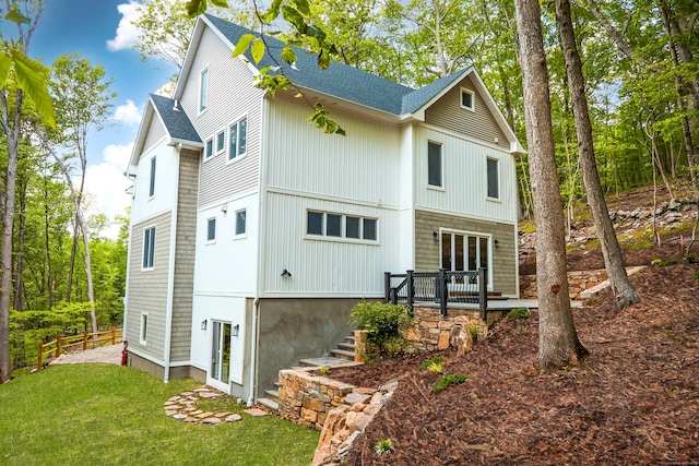 rear view of house with a wooden deck and a lawn