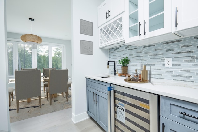 bar featuring wine cooler, sink, pendant lighting, decorative backsplash, and white cabinets