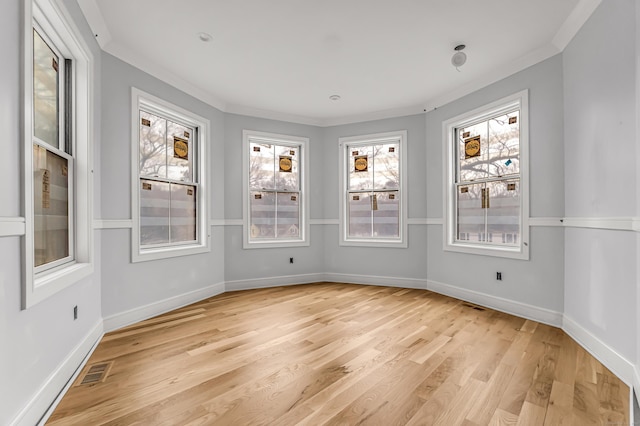 empty room with crown molding and light hardwood / wood-style floors