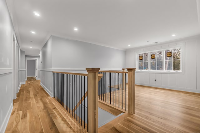 hallway featuring light wood-type flooring and ornamental molding