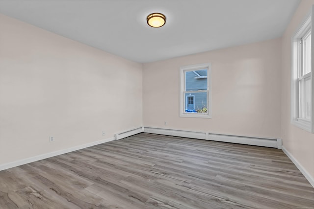 spare room featuring baseboard heating and light wood-type flooring