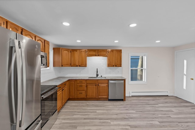 kitchen featuring a baseboard heating unit, stainless steel appliances, tasteful backsplash, sink, and light hardwood / wood-style flooring