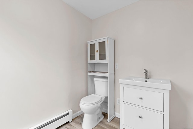 bathroom featuring vanity, toilet, a baseboard heating unit, and hardwood / wood-style flooring