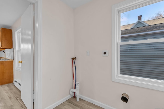 laundry area with sink, light wood-type flooring, electric dryer hookup, and a baseboard heating unit