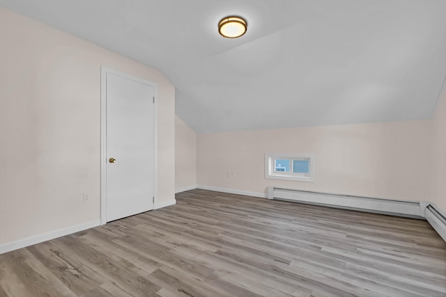 additional living space featuring baseboard heating, light hardwood / wood-style floors, and lofted ceiling