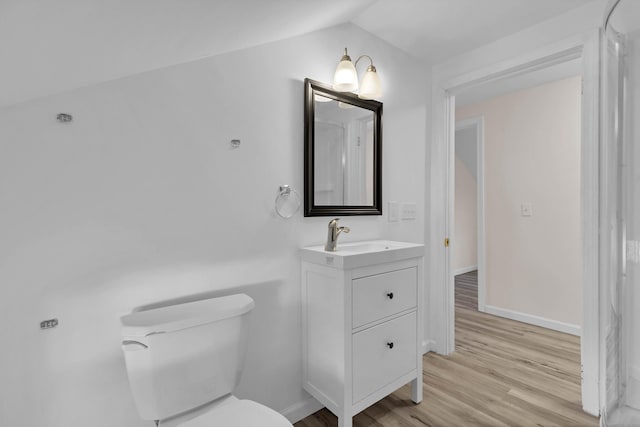 bathroom featuring hardwood / wood-style flooring, toilet, lofted ceiling, and vanity