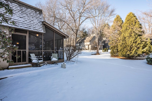 yard layered in snow with a sunroom