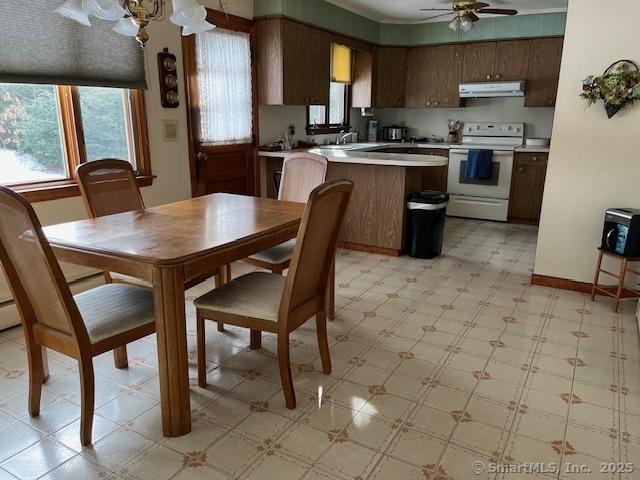 kitchen with ceiling fan with notable chandelier, white electric range, sink, dark brown cabinetry, and kitchen peninsula