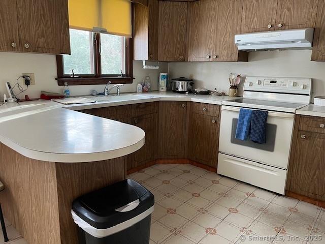 kitchen featuring white electric range oven, range hood, sink, and kitchen peninsula