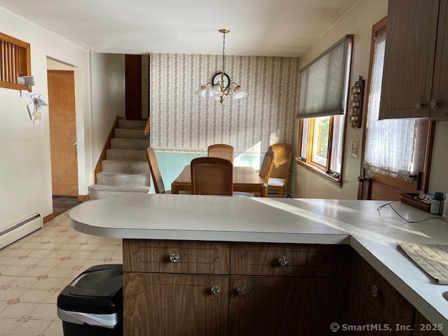 kitchen with hanging light fixtures, a baseboard heating unit, dark brown cabinetry, and kitchen peninsula