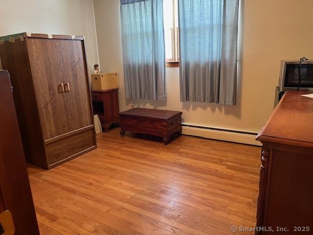 bedroom with a baseboard radiator and light wood-type flooring