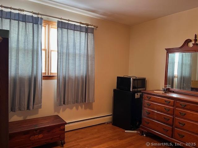 bedroom featuring hardwood / wood-style flooring and a baseboard radiator