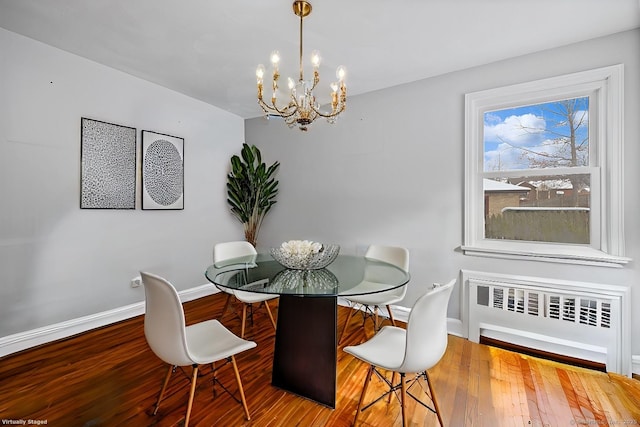 dining room featuring hardwood / wood-style flooring, radiator heating unit, and an inviting chandelier