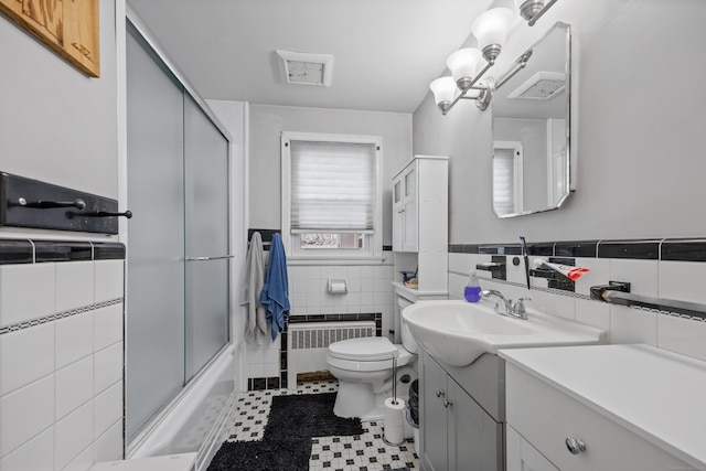 full bathroom with enclosed tub / shower combo, tile walls, radiator heating unit, vanity, and toilet