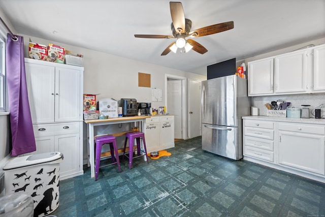 kitchen featuring ceiling fan, stainless steel refrigerator, and white cabinets